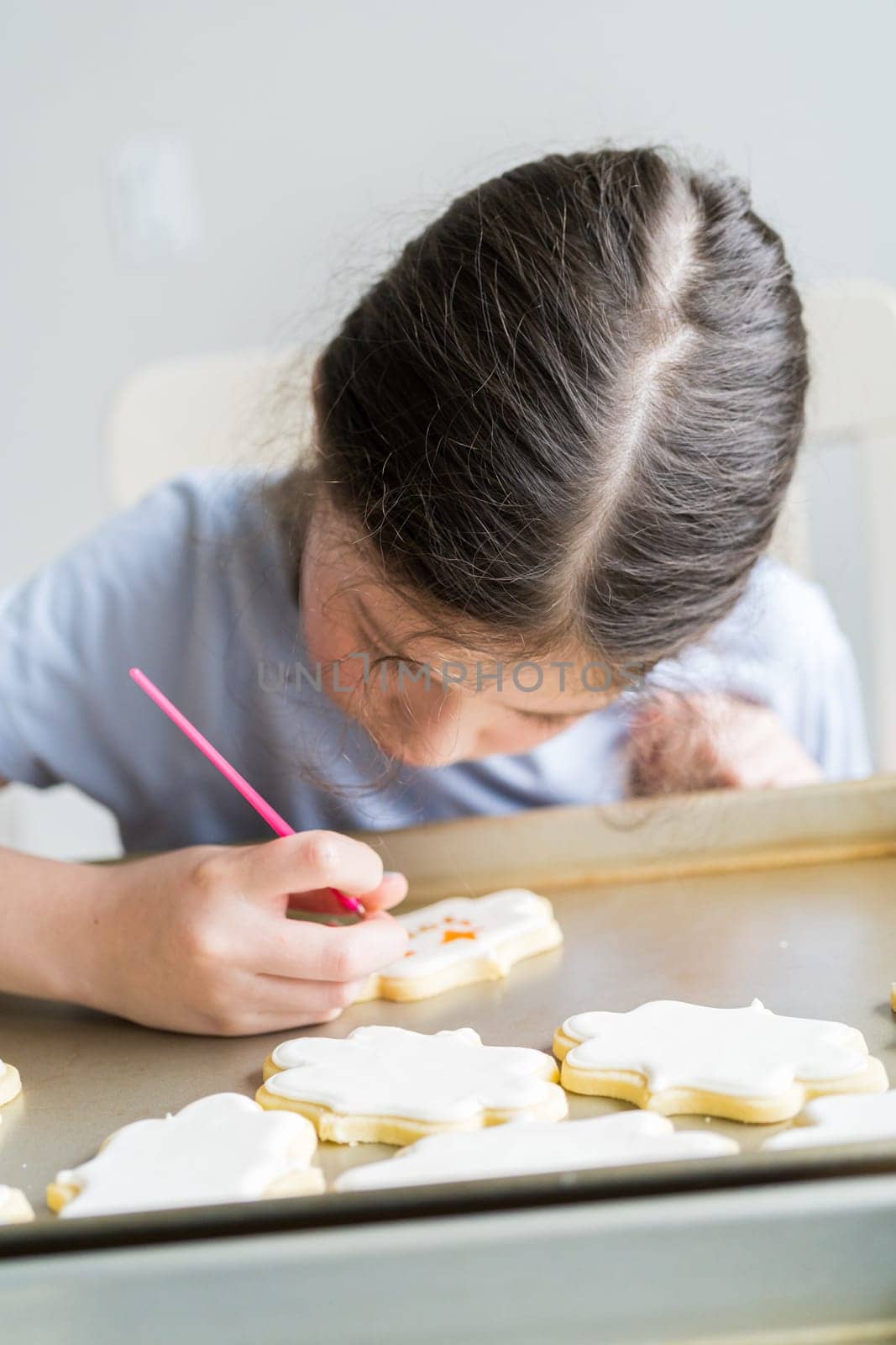 A heartwarming scene of a little girl carefully writing 'Sorry' on sugar cookies with food coloring, the cookies beautifully flooded with white royal icing.