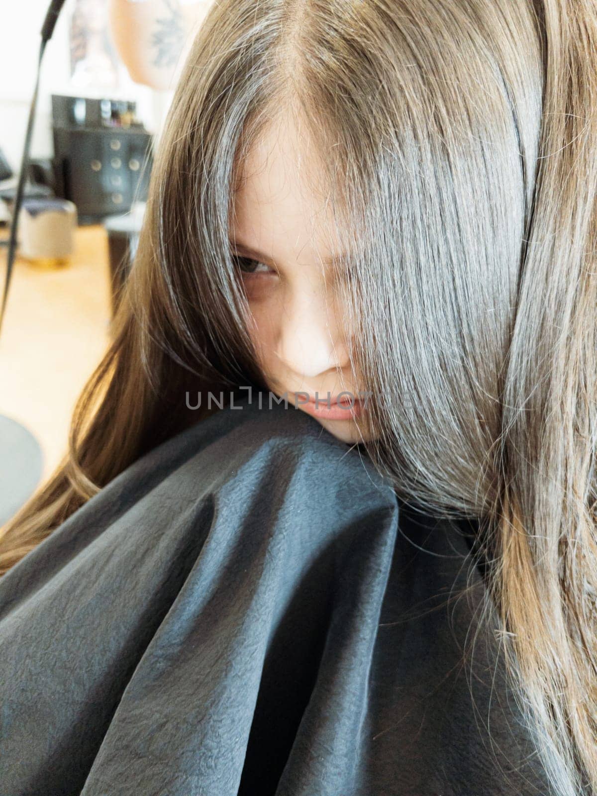 Gentle hands maneuver a hair dryer through a young girl's newly cut hair, showcasing the drying process after a meticulous trim. The warmth of the dryer breathes life into her locks, as they transform from damp to styled with care and expertise.