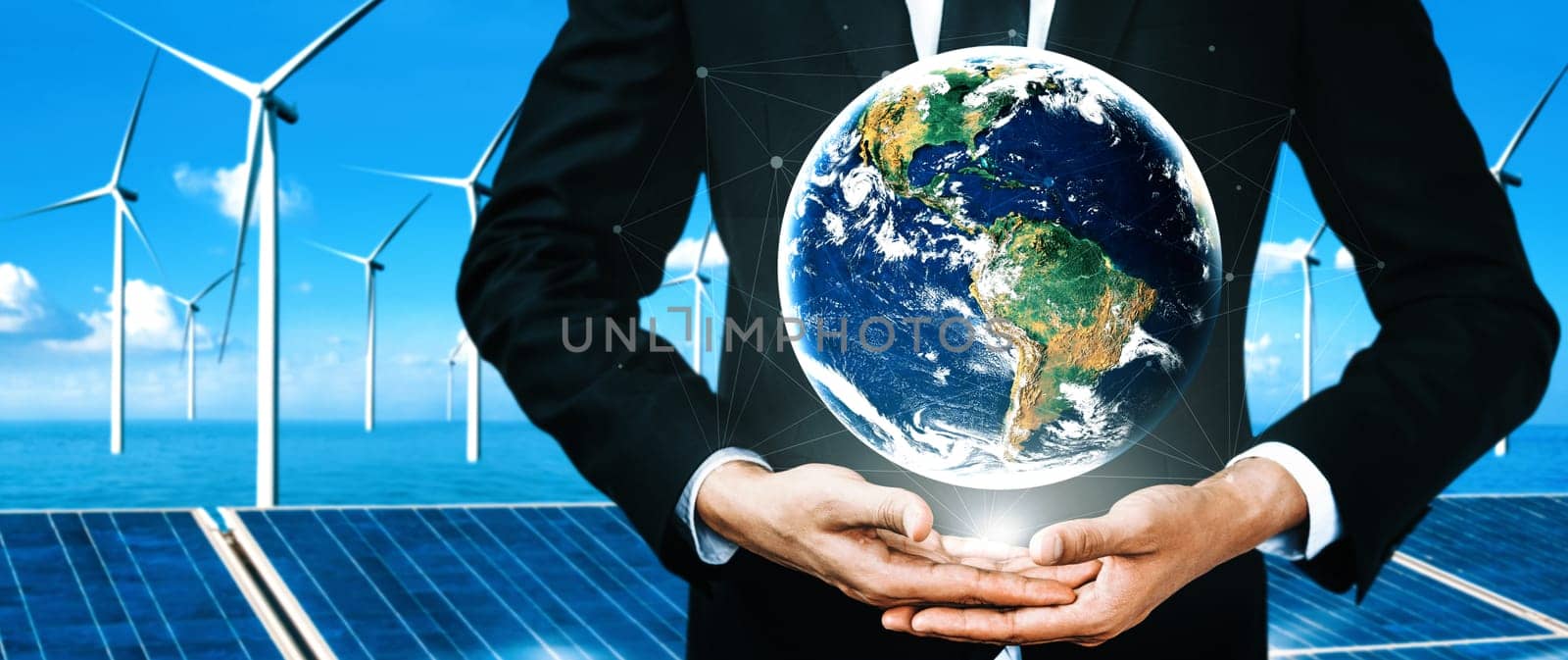 Concept of sustainability development by alternative energy. Man hand take care of planet earth with environmentally friendly wind turbine farm and green renewable energy in background. uds