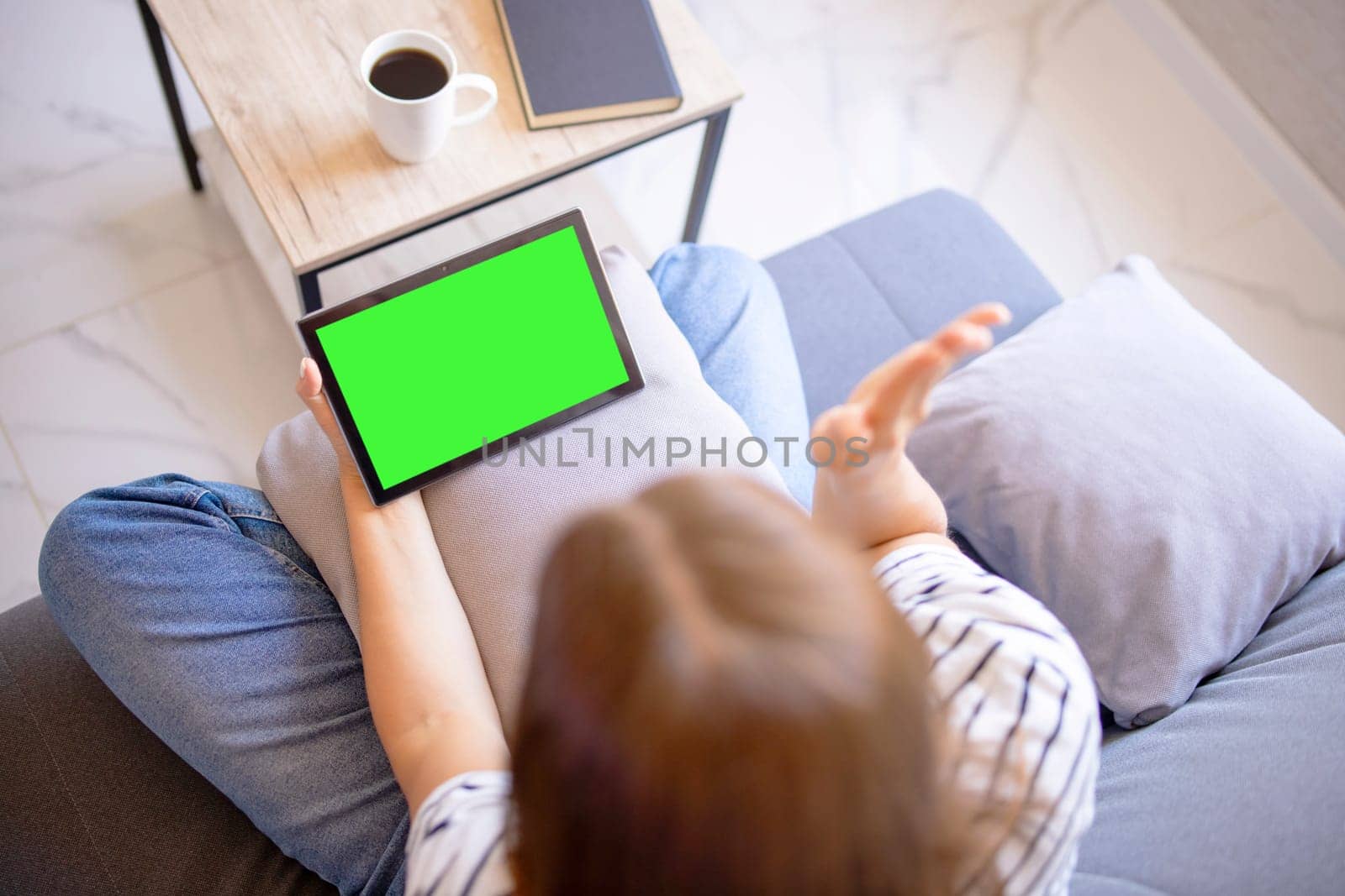 Over-shoulder view of a tablet with a green screen held by a person