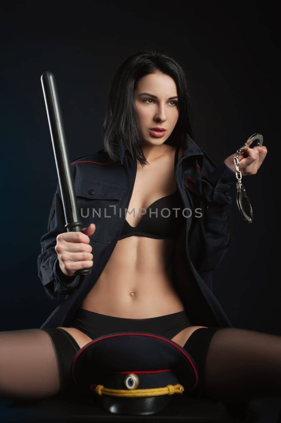 sexy girl in a military police uniform on a dark background with handcuffs and a rubber button, role-playing and striptease for adults by Rotozey