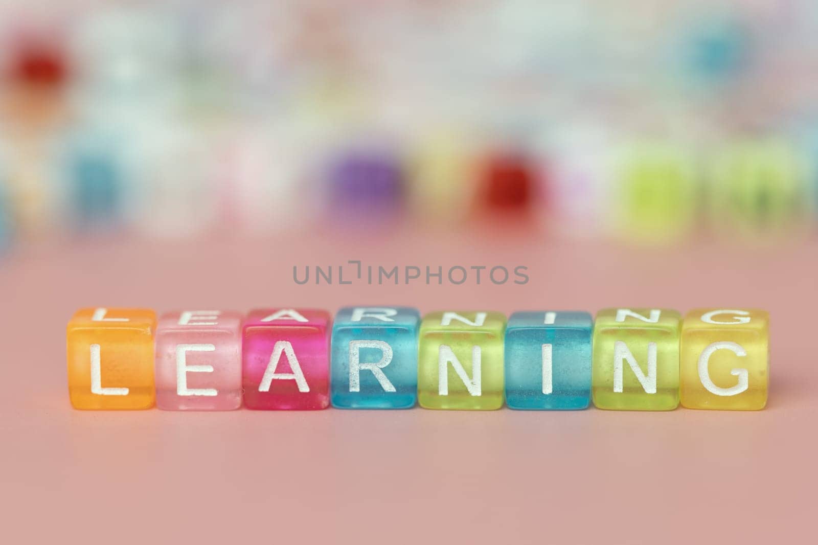 The word Learning formed with multicolored cubes on a pink background for education and studying concept, selective focus image