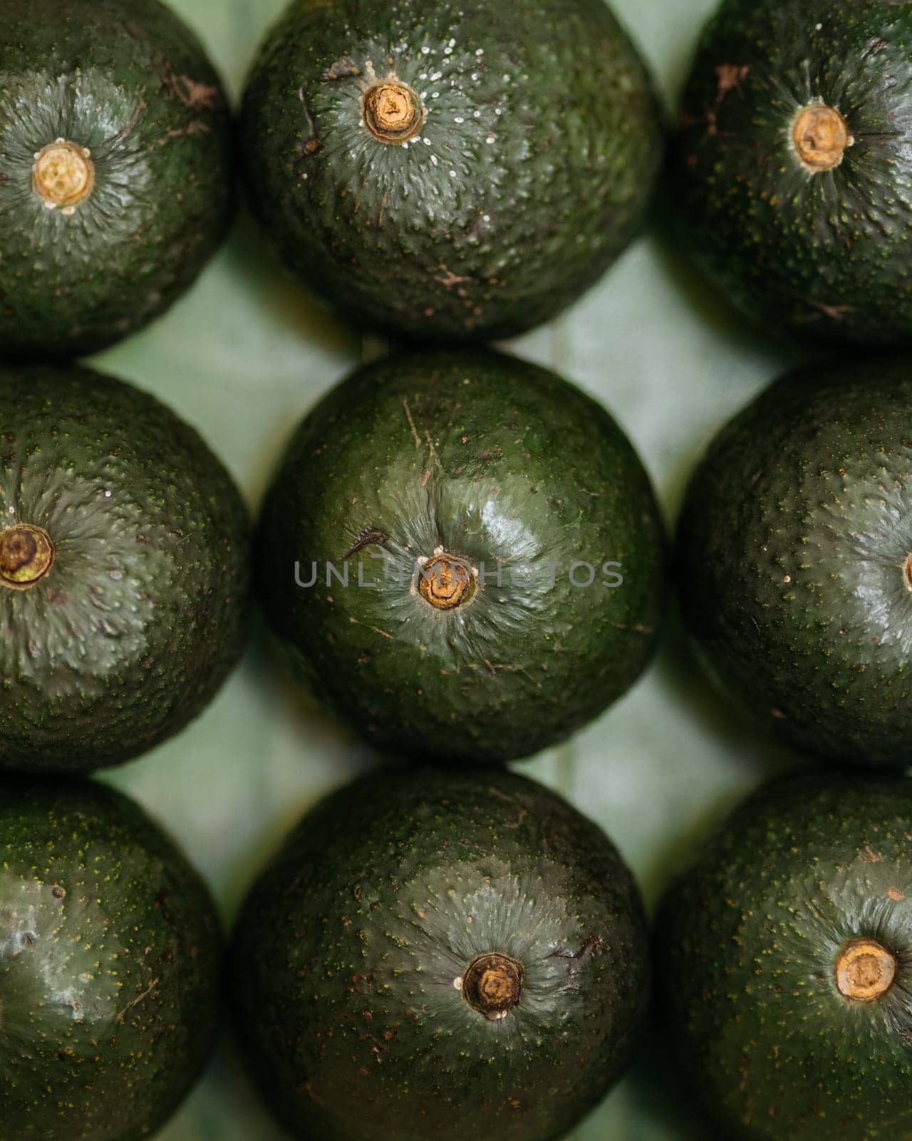 Close-up of fresh avocados arranged neatly on a textured surface by apavlin