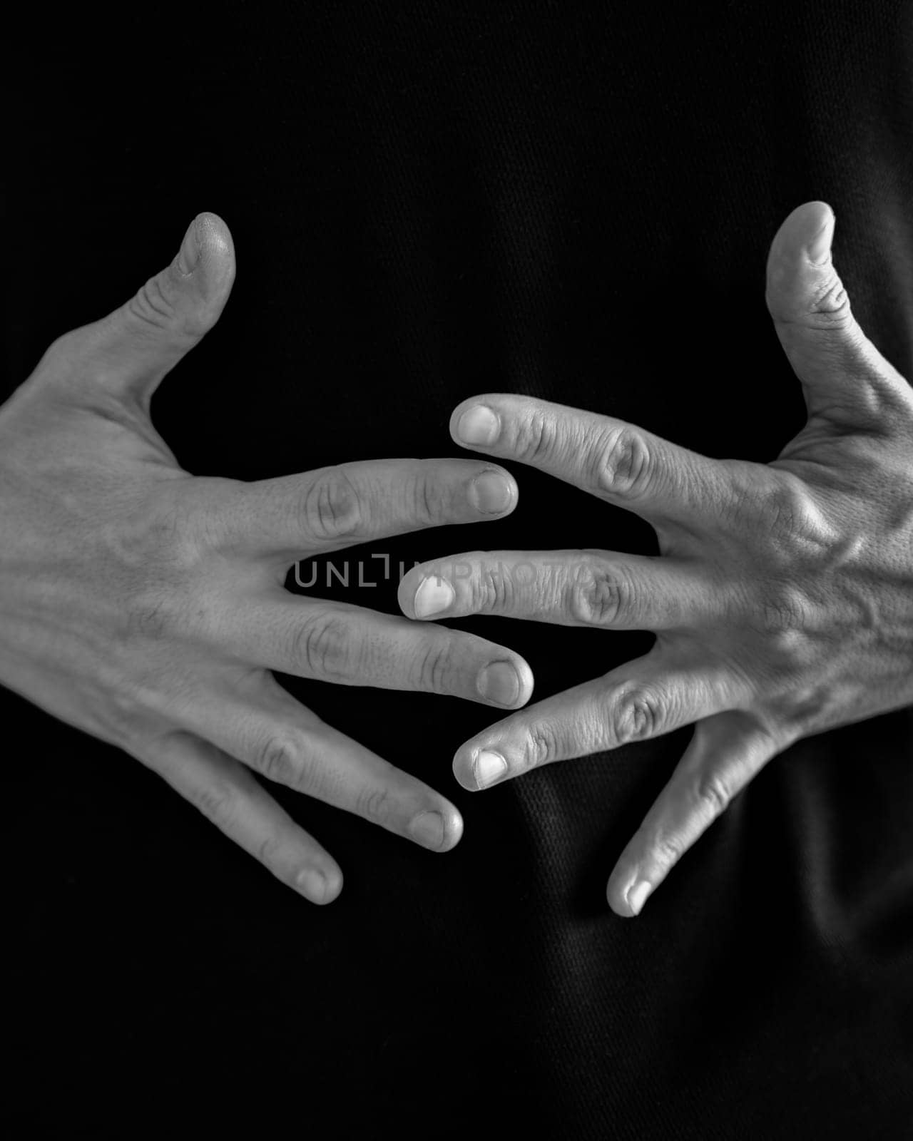 Overlapping hands creating an intricate pattern against a black textile backdrop