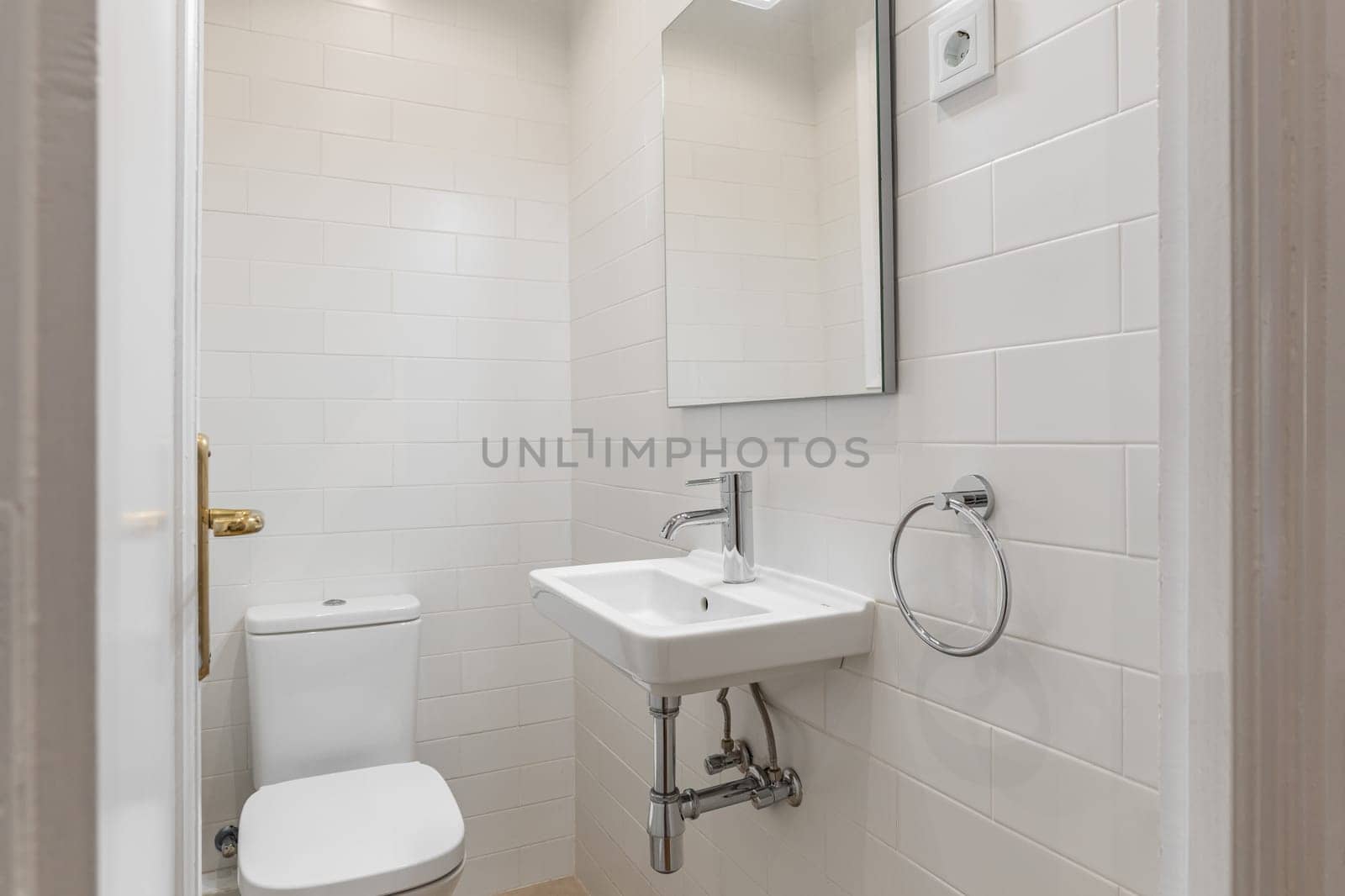 Compact and clean bathroom space with white subway tiles, modern sink, and silver fixtures.