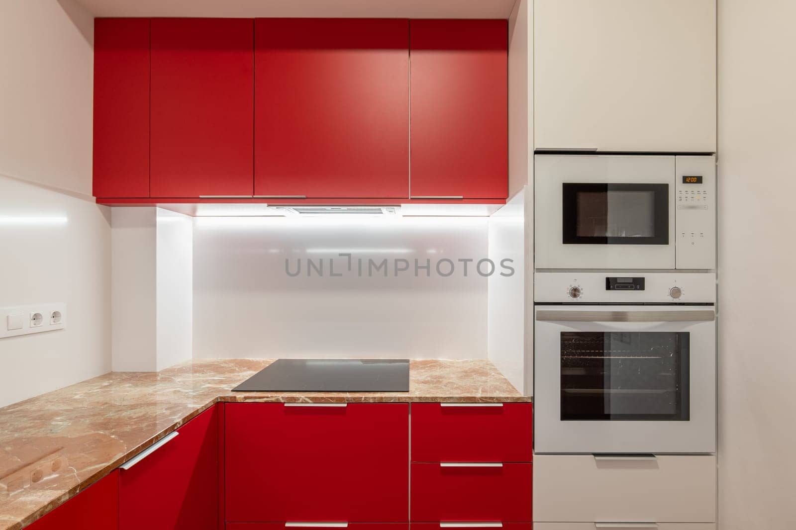 Vibrant red kitchen cabinets with modern appliances and marble countertop by apavlin