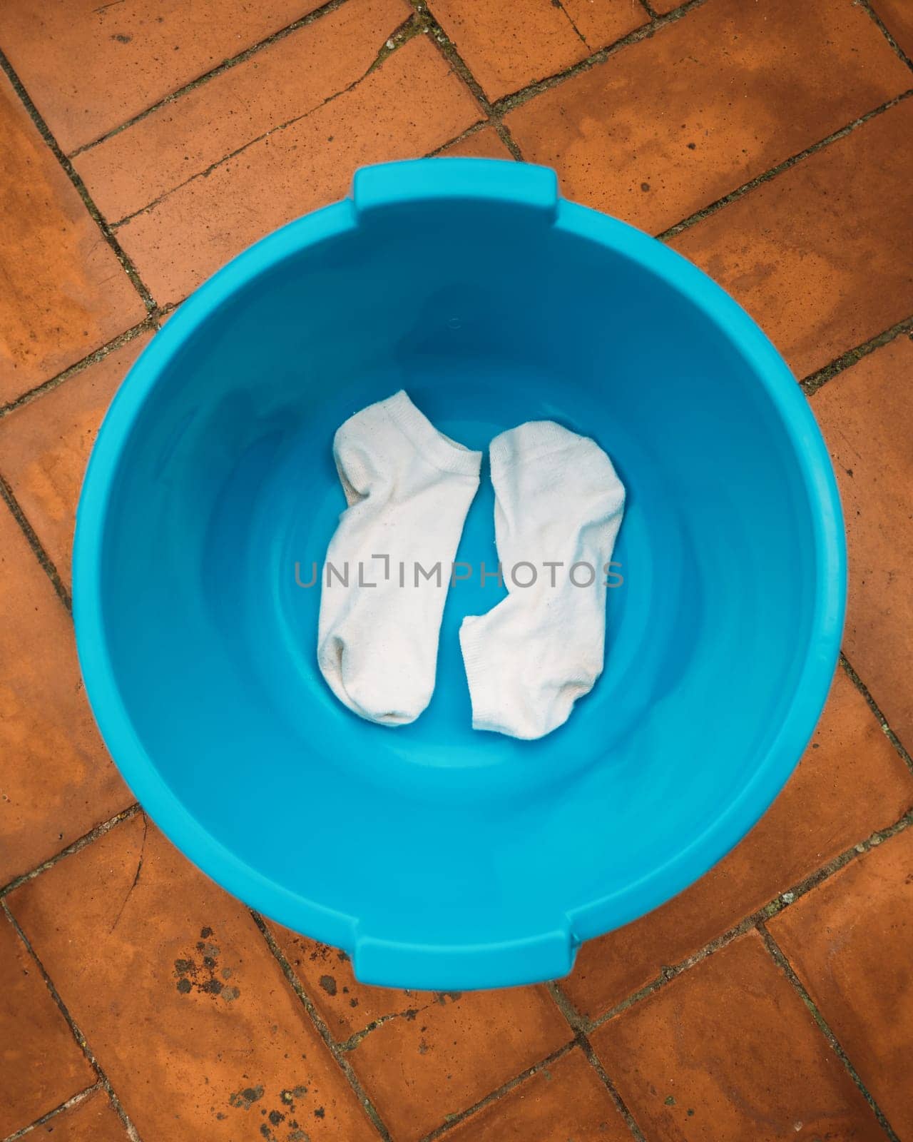 A pair of white socks in a blue plastic basin.