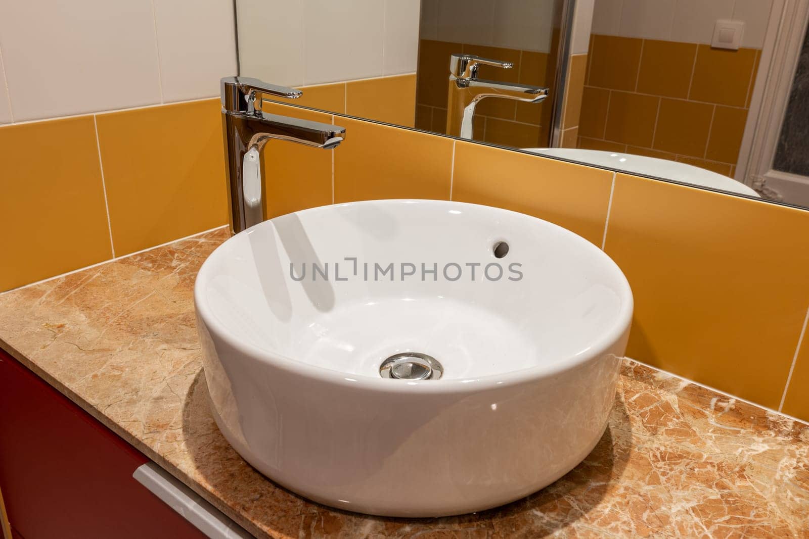 Modern bathroom interior with a white vessel sink and vibrant yellow tiles by apavlin