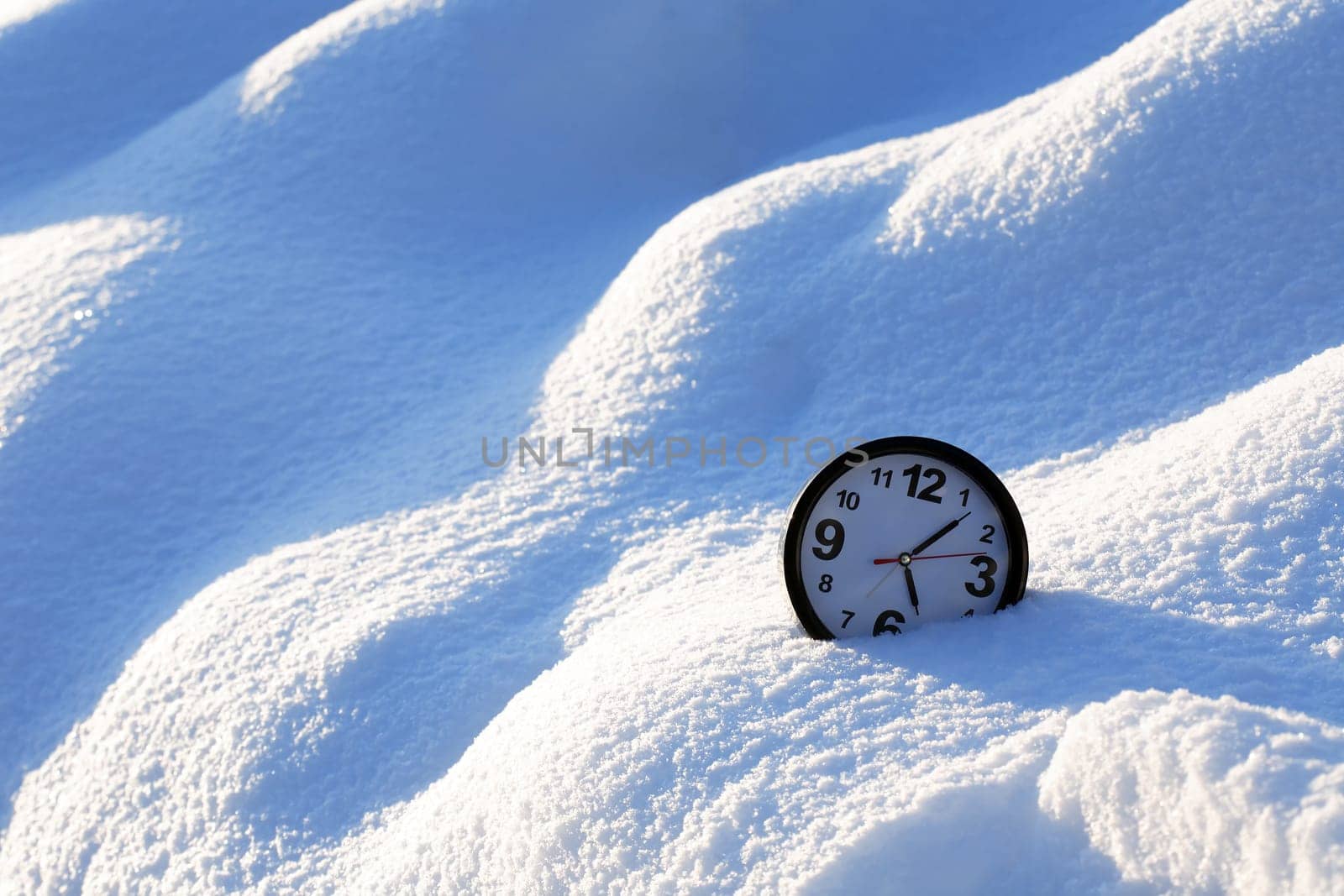 Clocks in the snow on the background of a winter landscape
