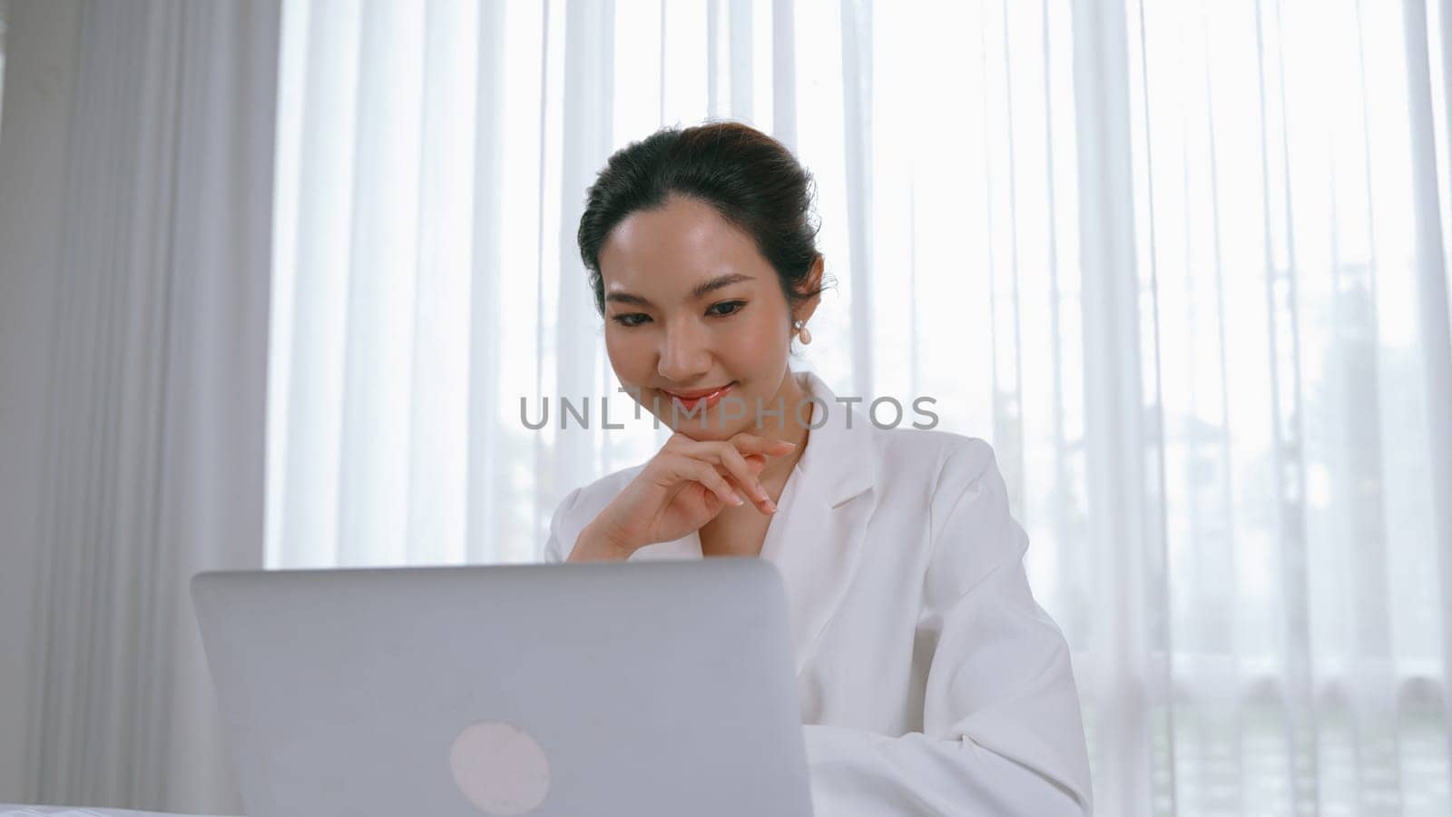 Young businesswoman sitting on the workspace desk using laptop computer for internet online content writing or secretary remote working from home. Vivancy