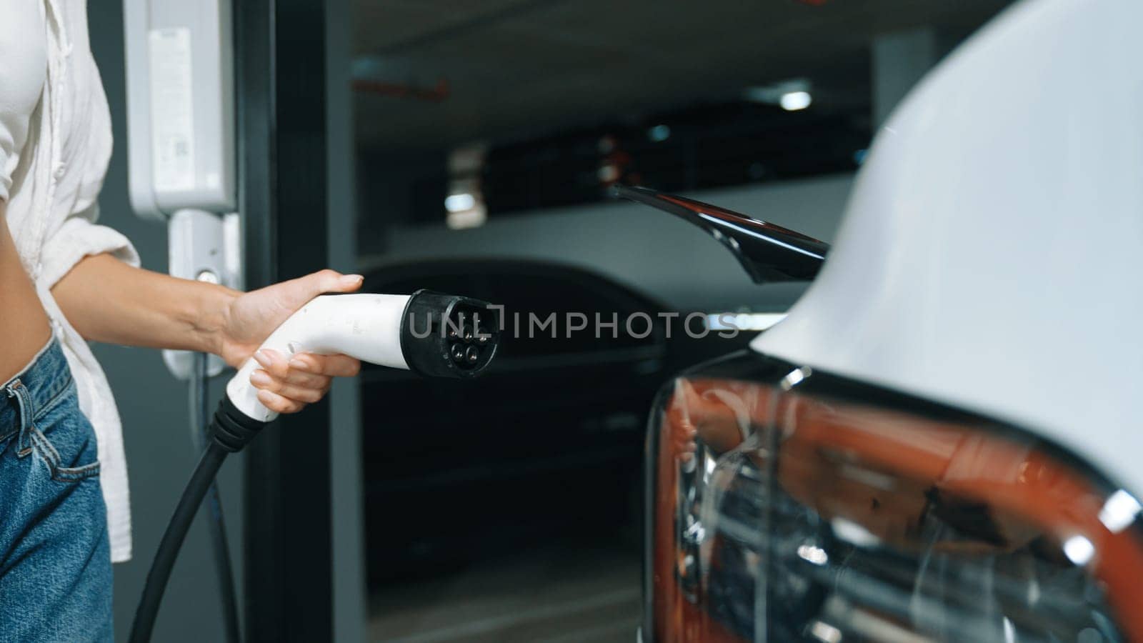 Young woman travel with EV electric car to shopping center parking lot innards by biancoblue