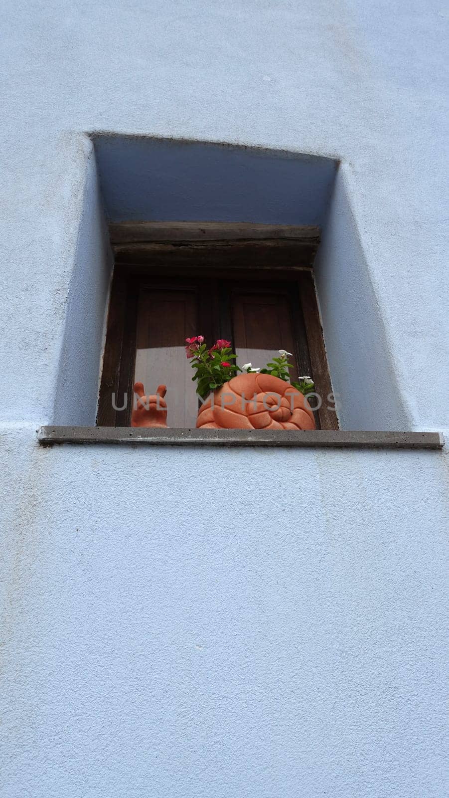 Posada, Italy, August 1 2021. A terracotta snail on a window sill during a summer day.