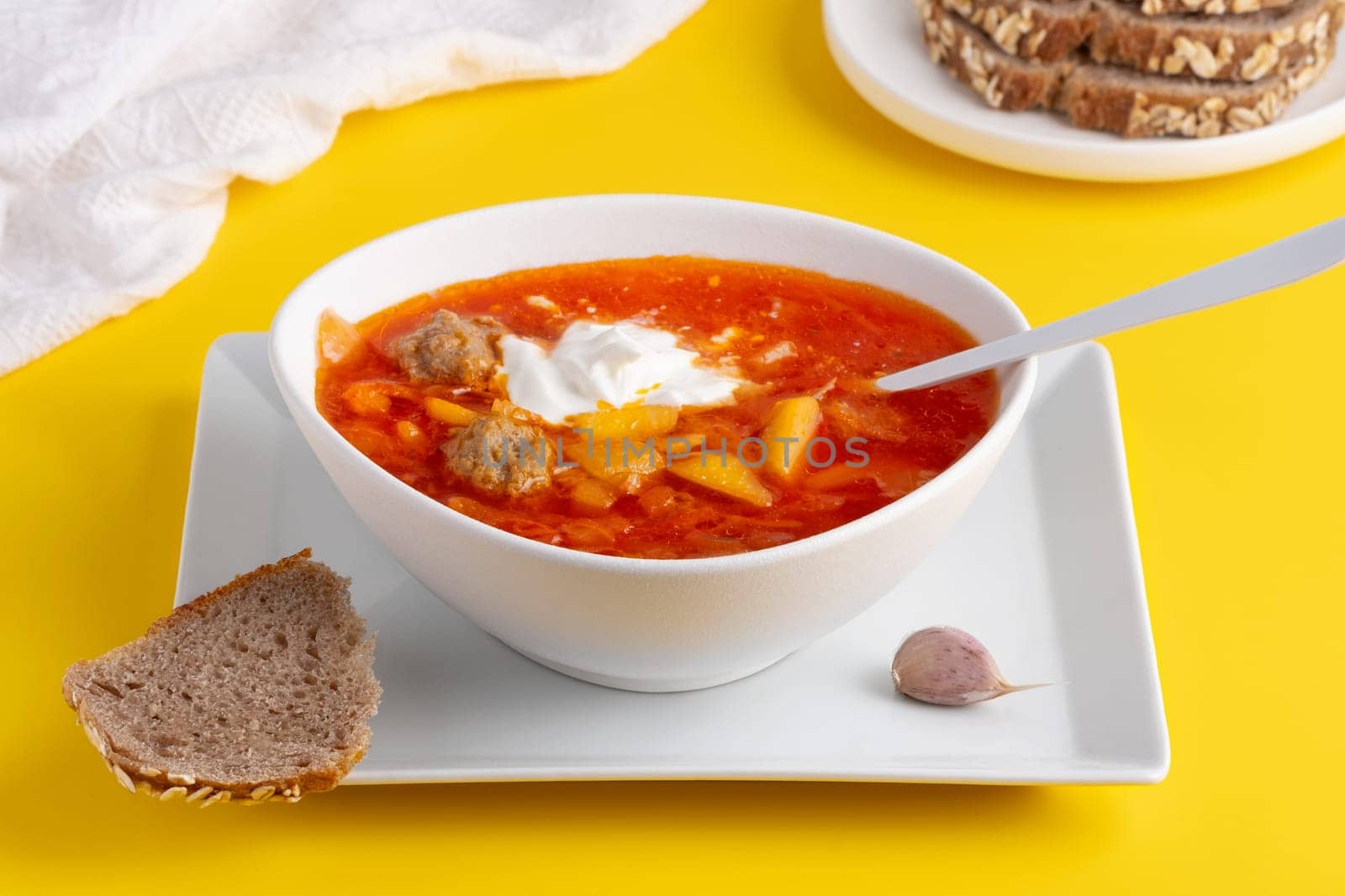 Ukrainian and Russian cuisine. Red borscht. Soup of tomatoes, cabbage and vegetables. Borscht in a white bowl on a yellow background.