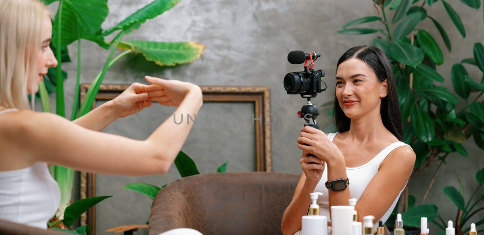 Two beautiful content creator making natural beauty and cosmetic tutorial on green plant garden video. Beauty blogger showing how to beauty care to social medial audience using selfie stick . Blithe