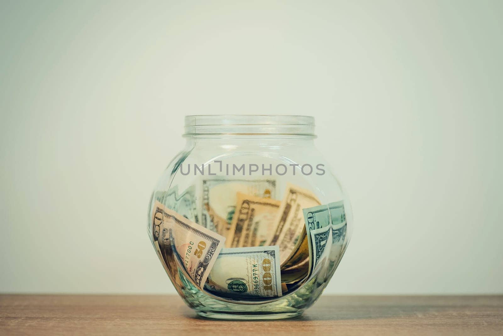 Toned photo of glass jar with saved dollar banknotes by VitaliiPetrushenko