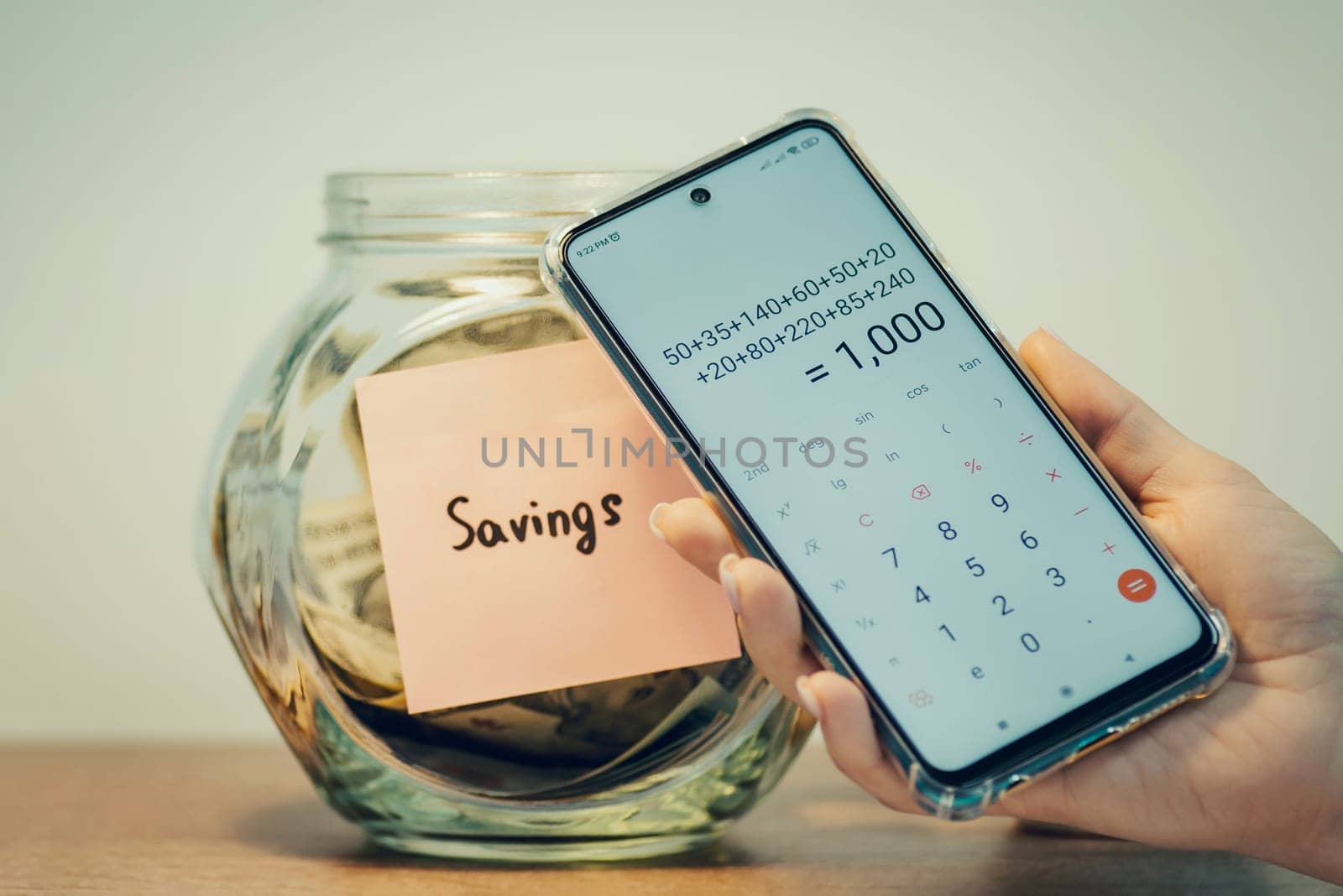 Counting saved up money dollars with mobile calculator, toned image by VitaliiPetrushenko