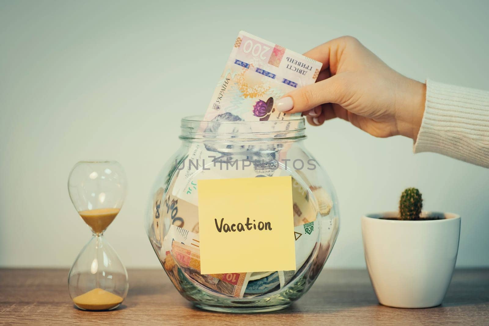 Ukrainian person putting 200 hryvnias to savings bank for vacation, toned photo by VitaliiPetrushenko