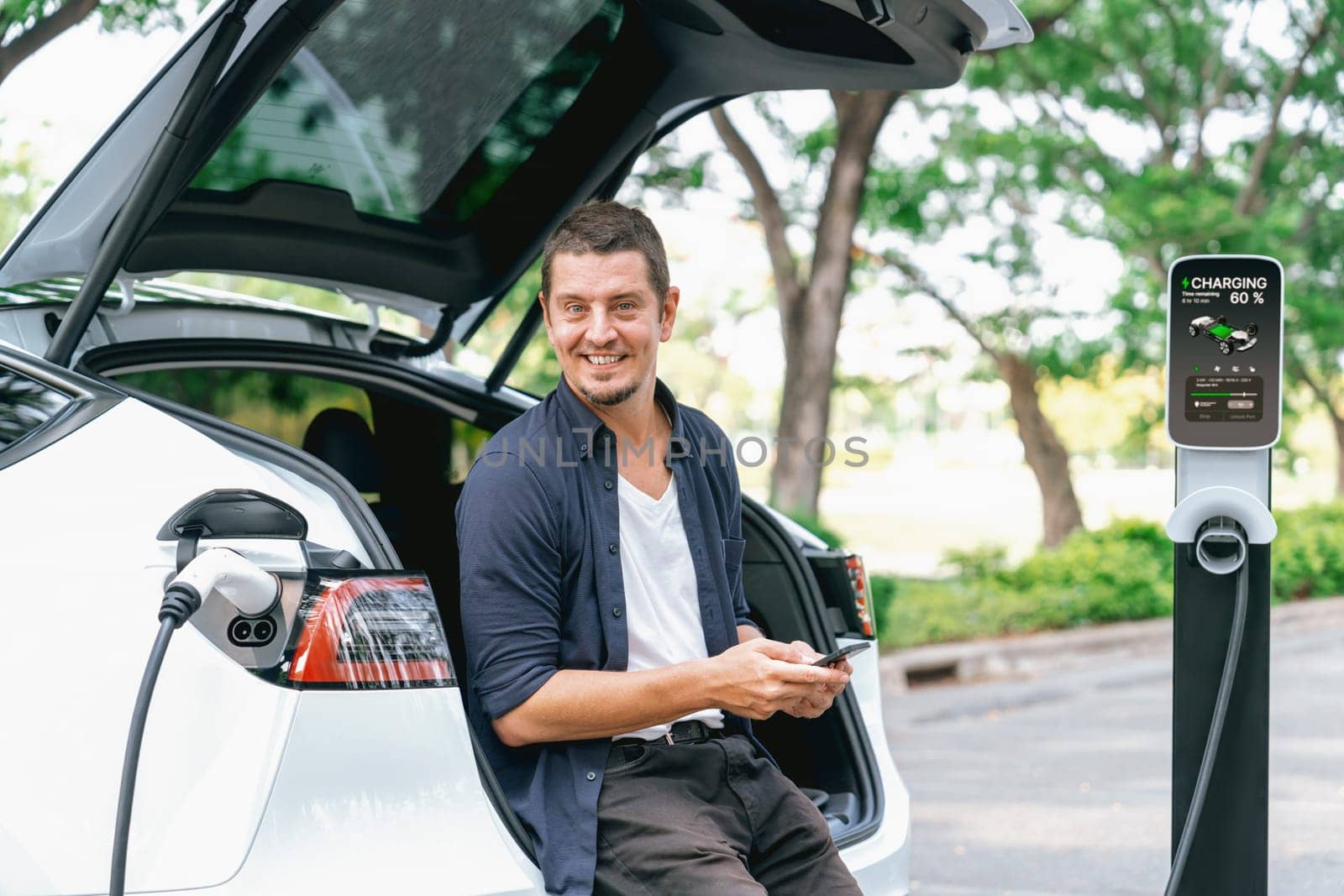 Man using smartphone to pay for electric car charging. Exalt by biancoblue