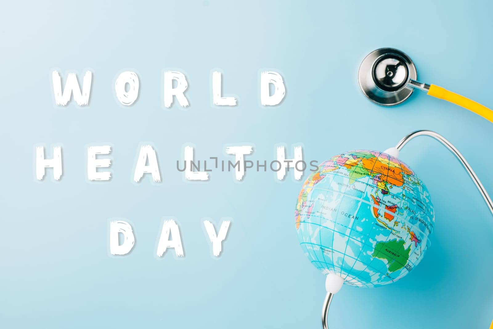 World Health Day Concept. Top view yellow doctor stethoscope and world globe isolated on pastel blue background with copy space, Save world day, Environment Green Earth, Health care and medical