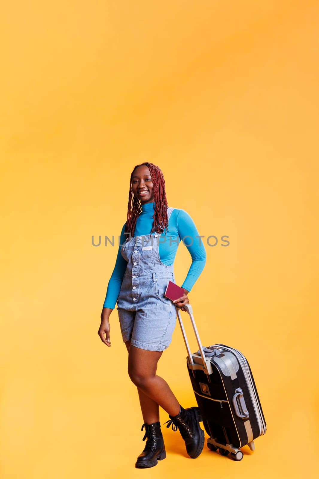 Tourist with identification passport travelling with trolley bags and luggage in studio, weekend activities. Young woman holding id pass to leave on international destination for getaway.
