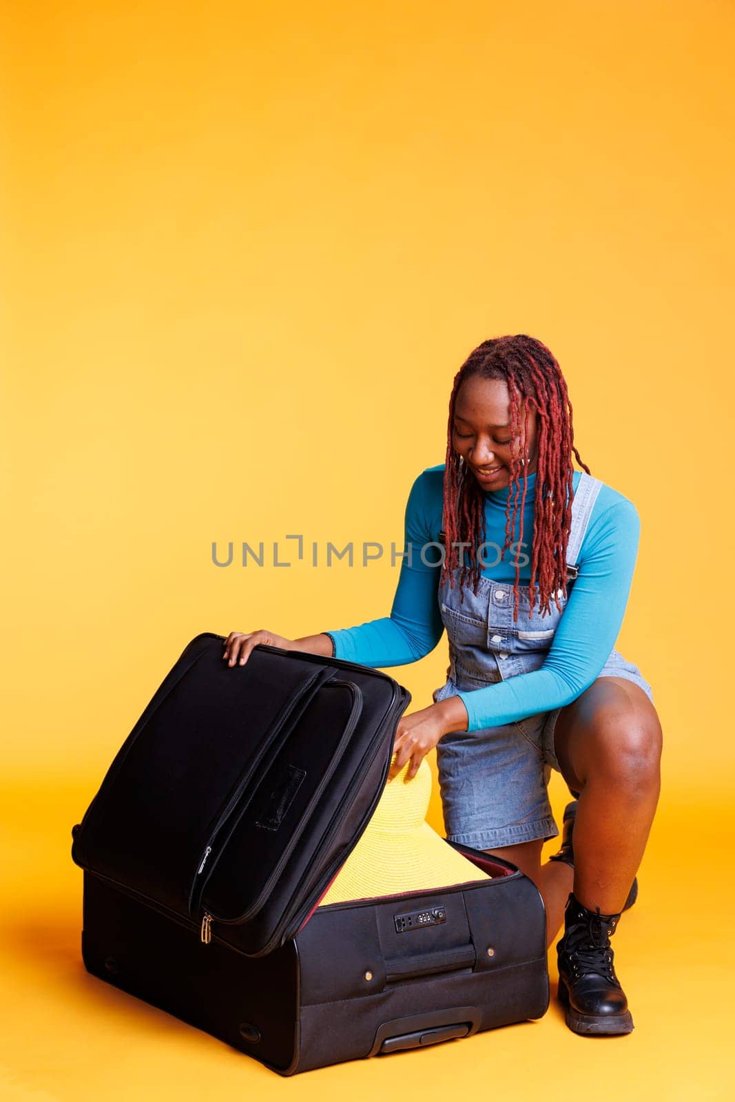 Female tourist packing bags for vacation, putting essentials and items in trolley bag before leaving on holiday trip. Young woman feeling excited about travelling, pack clothes.