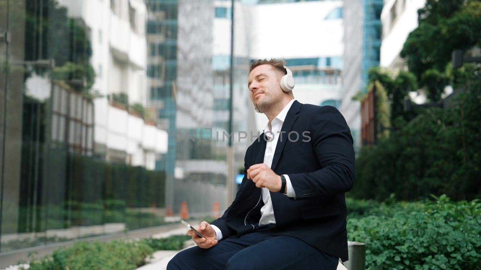 Caucasian businessman listening relaxing music while hold mobile phone. Urbane. by biancoblue