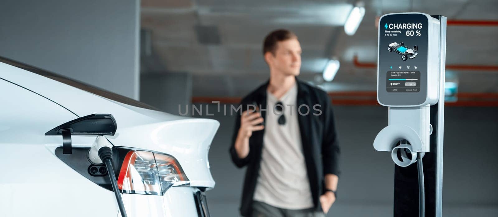 Young man travel with EV electric car to shopping center parking lot charging in downtown city showing urban sustainability lifestyle by green clean rechargeable energy of electric vehicle innards