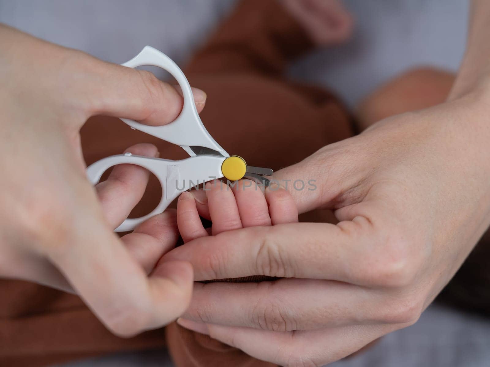 Mom cuts her newborn son's fingernails with small children's scissors. by mrwed54
