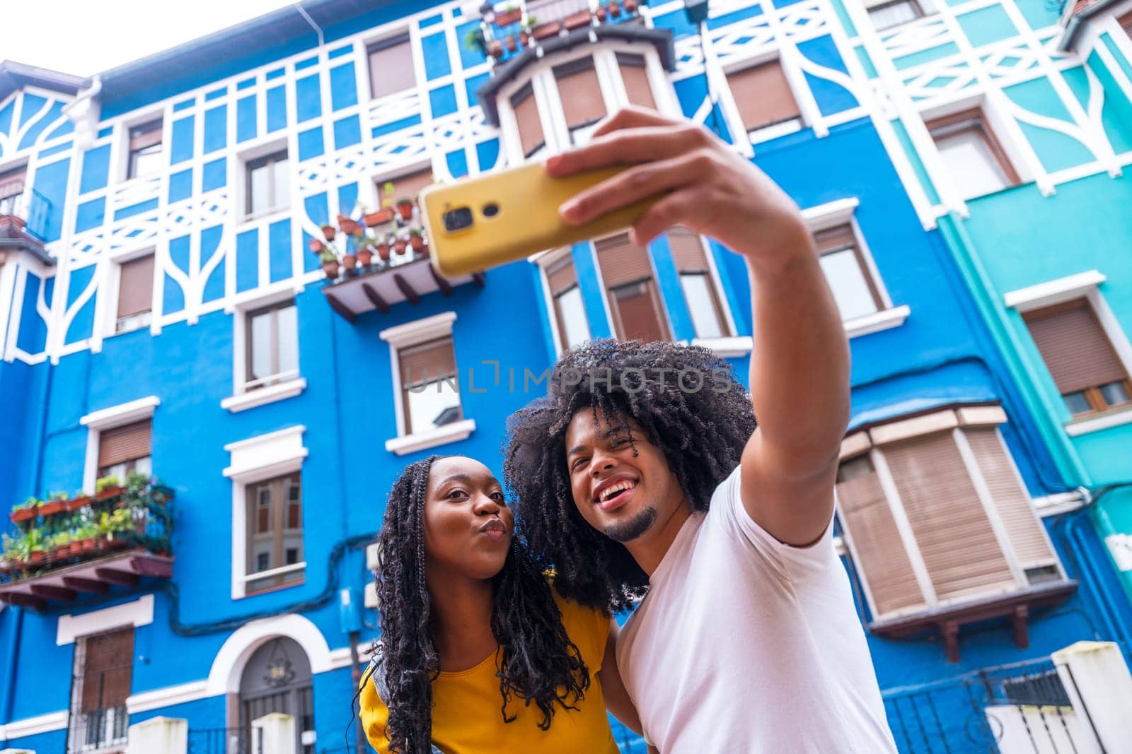 African american cool couple taking selfie with mobile in a street with colorful facades