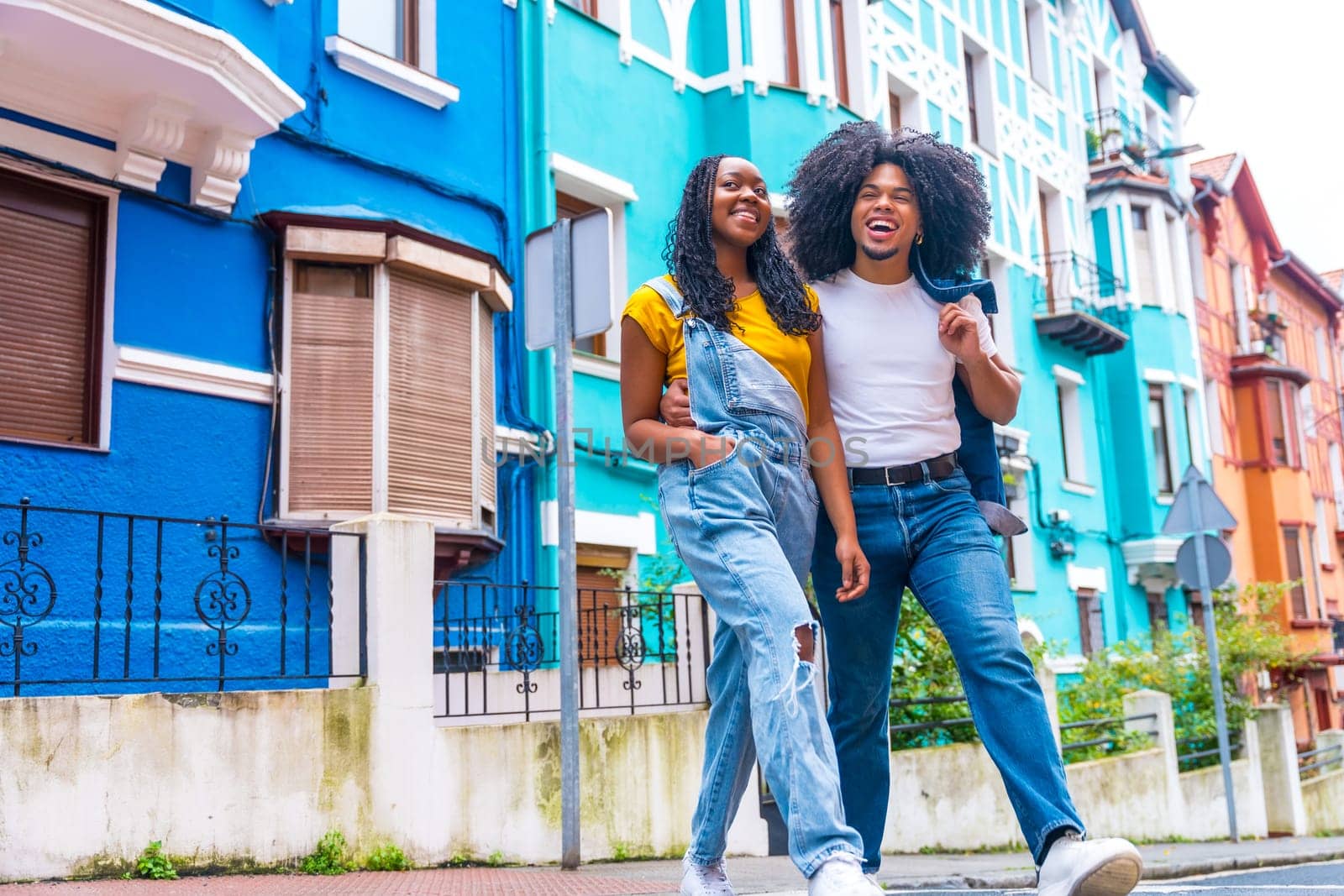 Low angle view horizontal photo of a cool african couple strolling along a colorful street