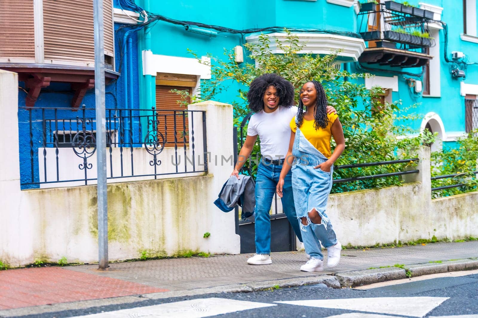 Wide view of a cool young african american couple exploring a city with colorful facades