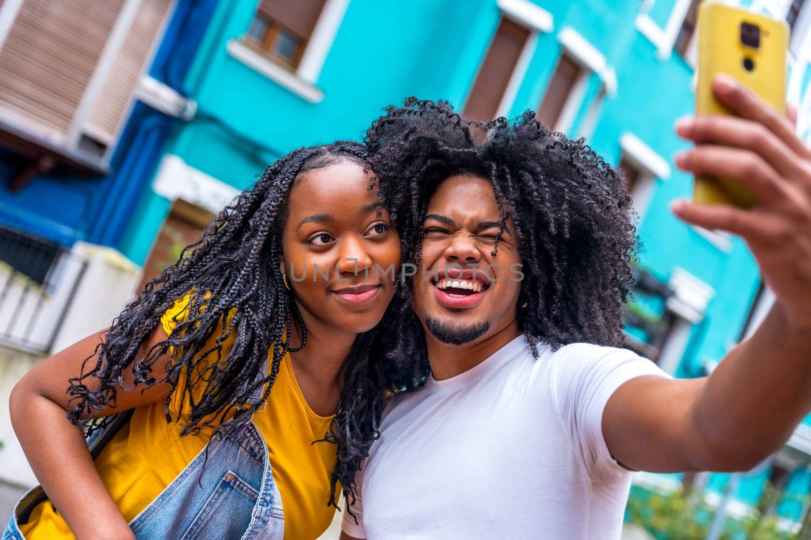Young african couple pulling faces taking selfie int he city by Huizi
