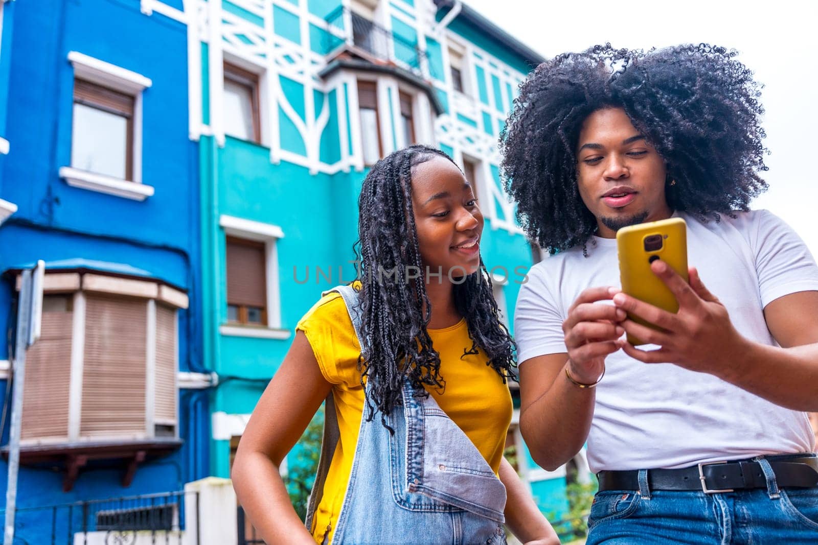 African couple looking for directions with the mobile exploring a city with colorful facades