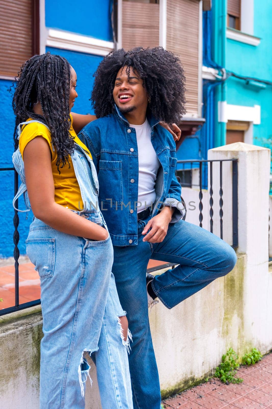 African american friends leaning outside a colorful house chatting by Huizi