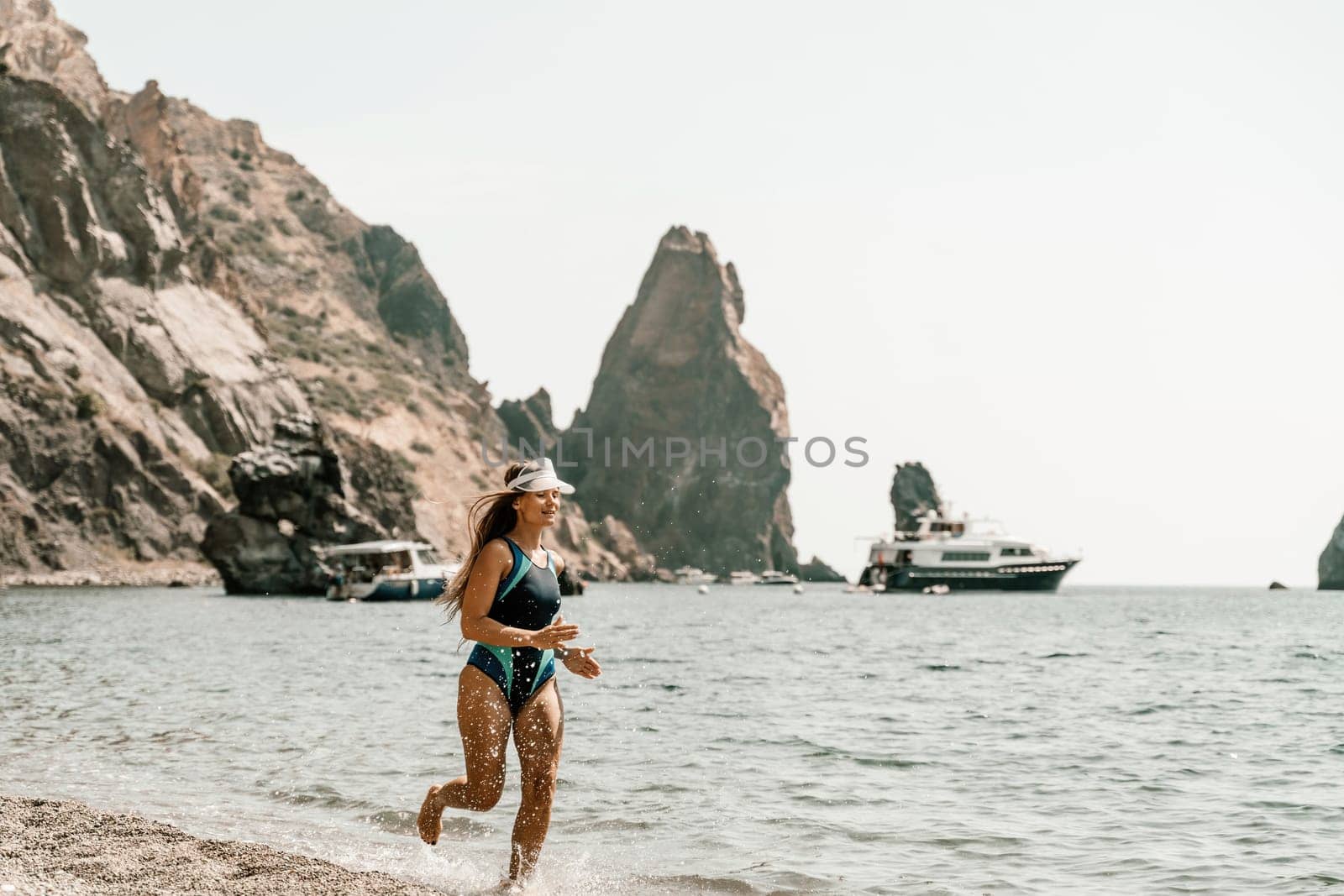 Woman beach vacation photo. A happy tourist in a blue bikini enjoying the scenic view of the sea and volcanic mountains while taking pictures to capture the memories of her travel adventure. by Matiunina