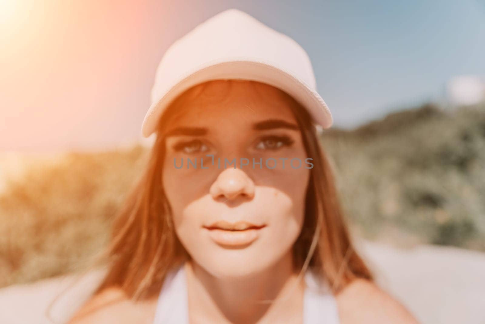 Woman travel sea. Happy tourist in hat enjoy taking picture outdoors for memories. Woman traveler posing on the beach at sea surrounded by volcanic mountains, sharing travel adventure journey by panophotograph