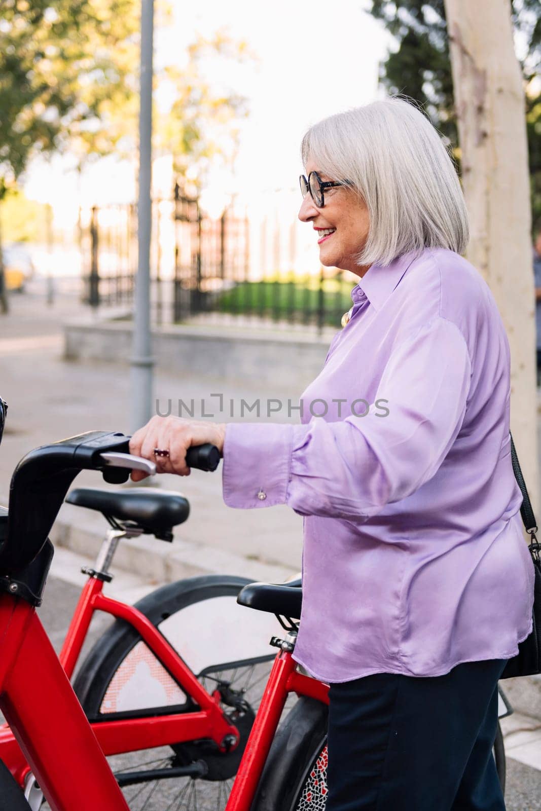 smiling senior woman taking rental bike by raulmelldo