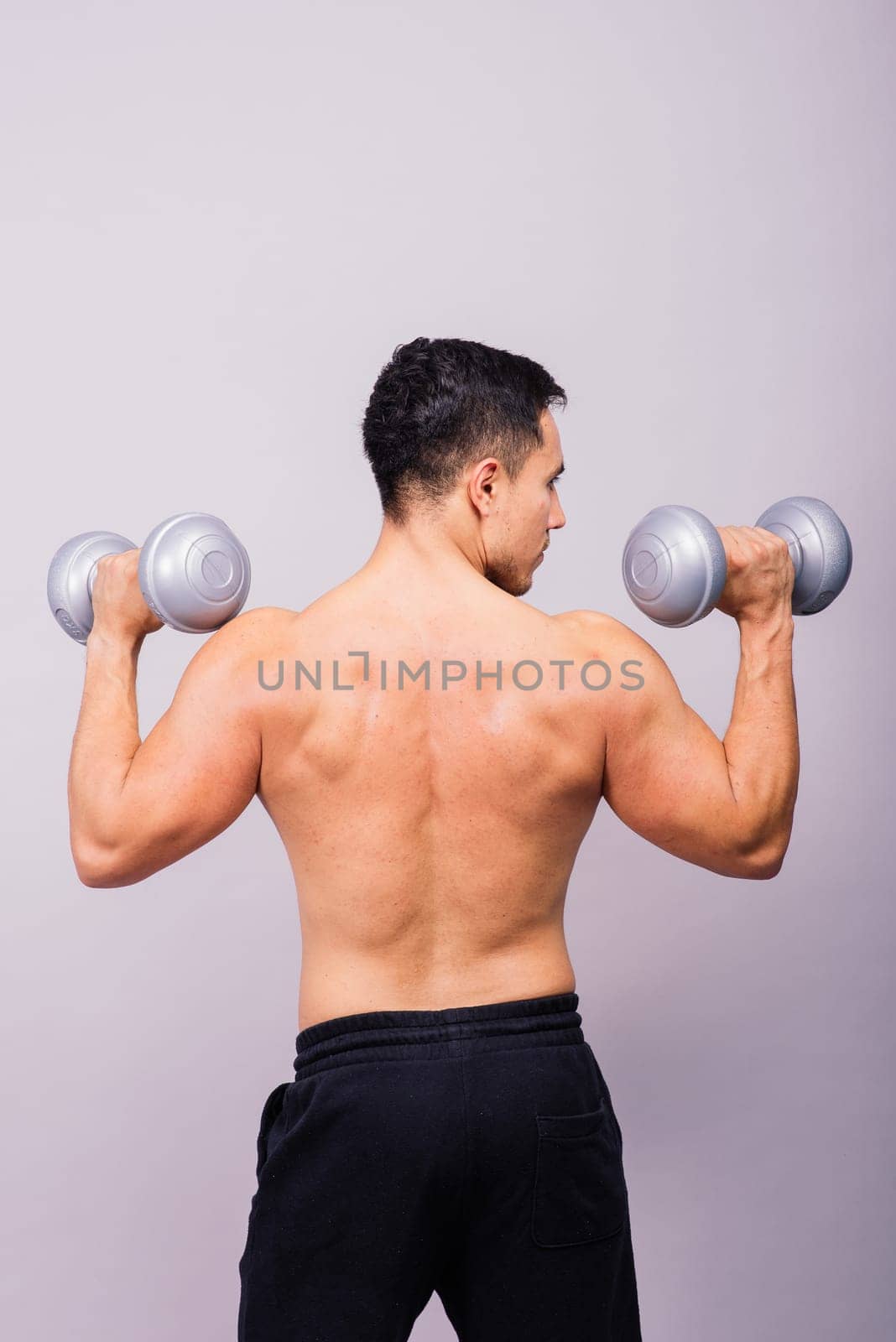 Shirtless bodybuilder showing his great body and holding dumbells.