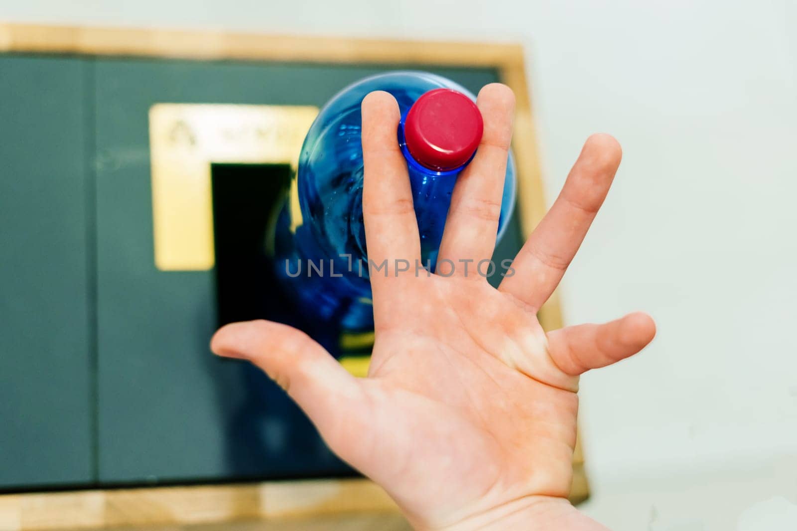 Close up hand throwing an empty plastic water bottle into recycling bin, recycle rubbish