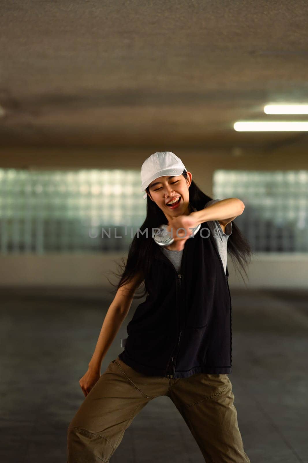 Cheerful young woman performing a Hip Hop dance in parking garage by prathanchorruangsak