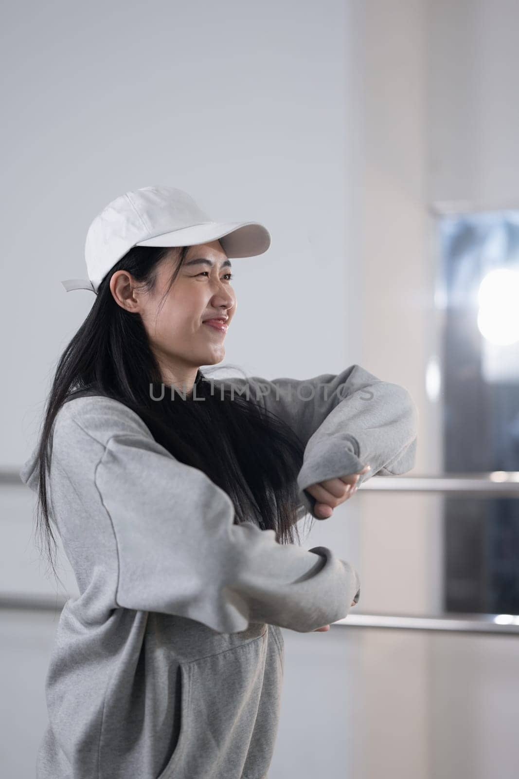 Pretty young woman in hoodie and cap enjoy practicing break dance at studio.