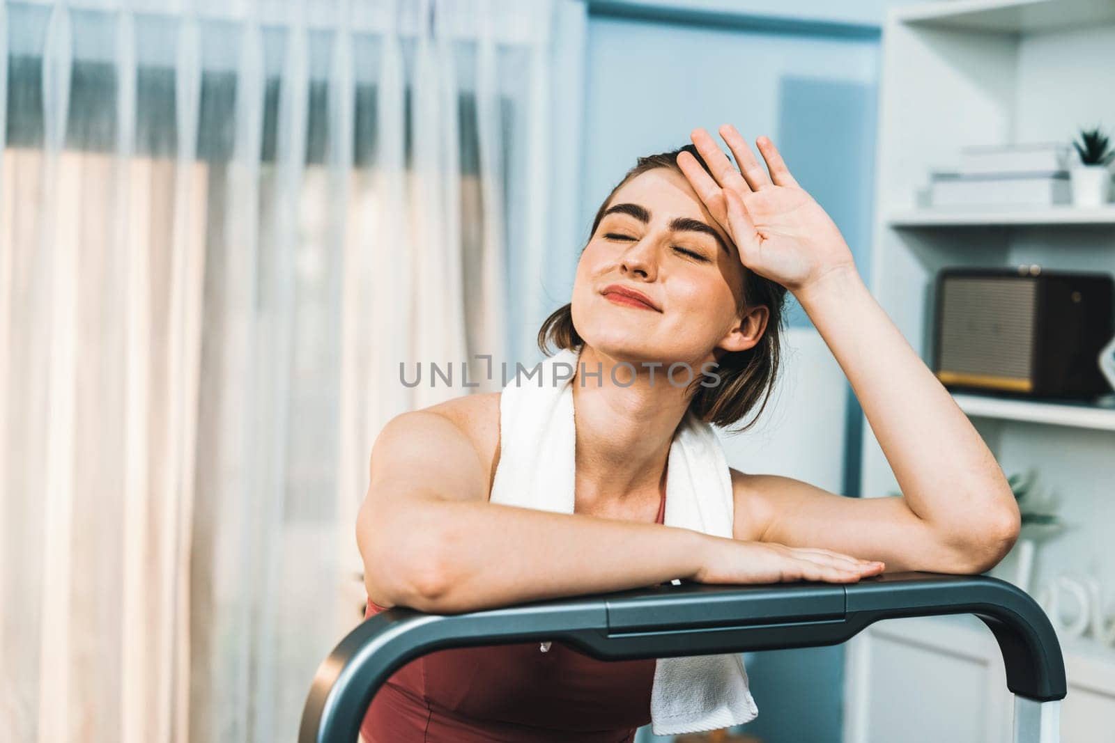 Athletic and sporty woman running on treadmill running machine during home body workout exercise session for fit physique and healthy sport lifestyle at home. Gaiety home exercise workout training.