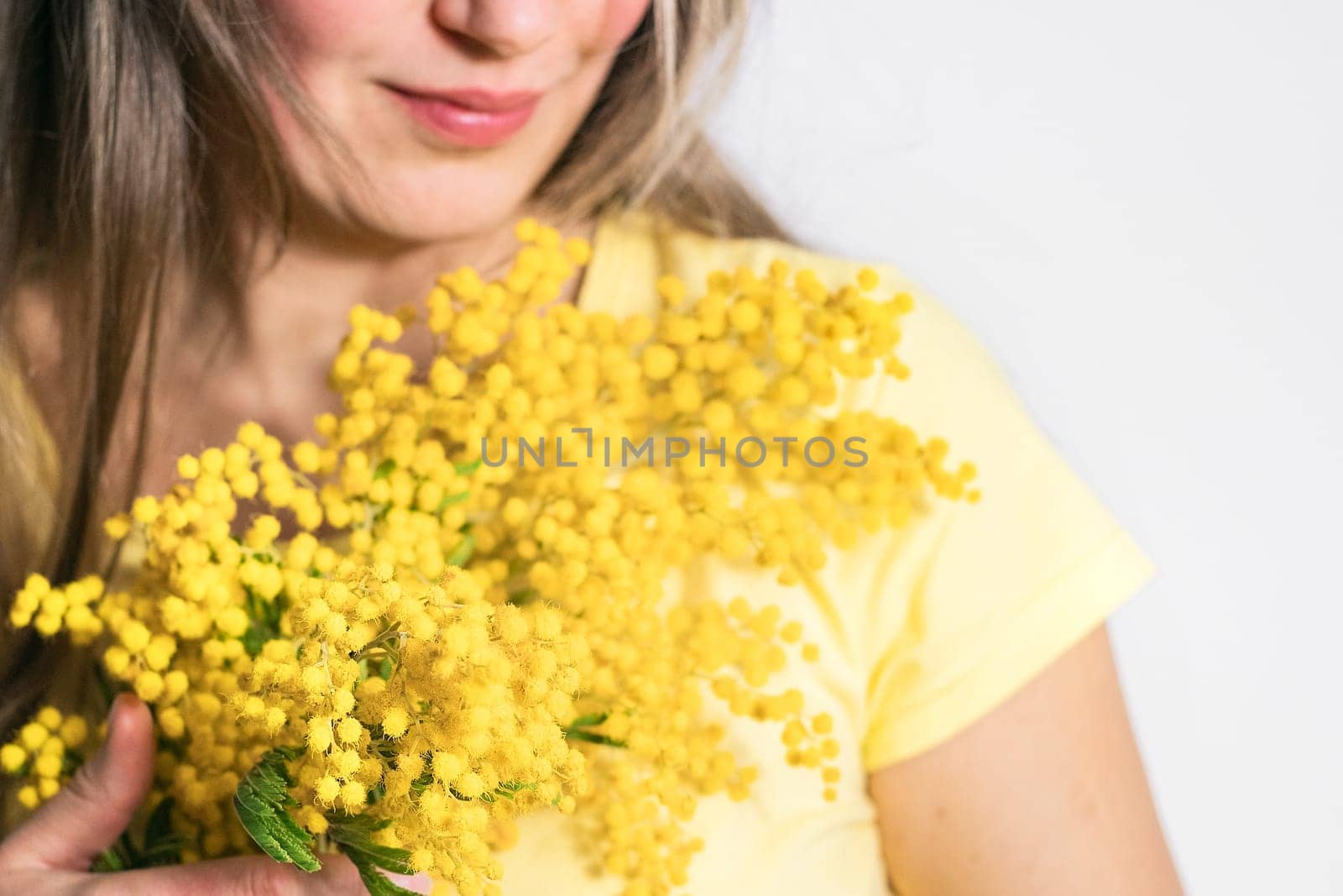 Beautiful young woman with mimosa flowers on white background. Close up