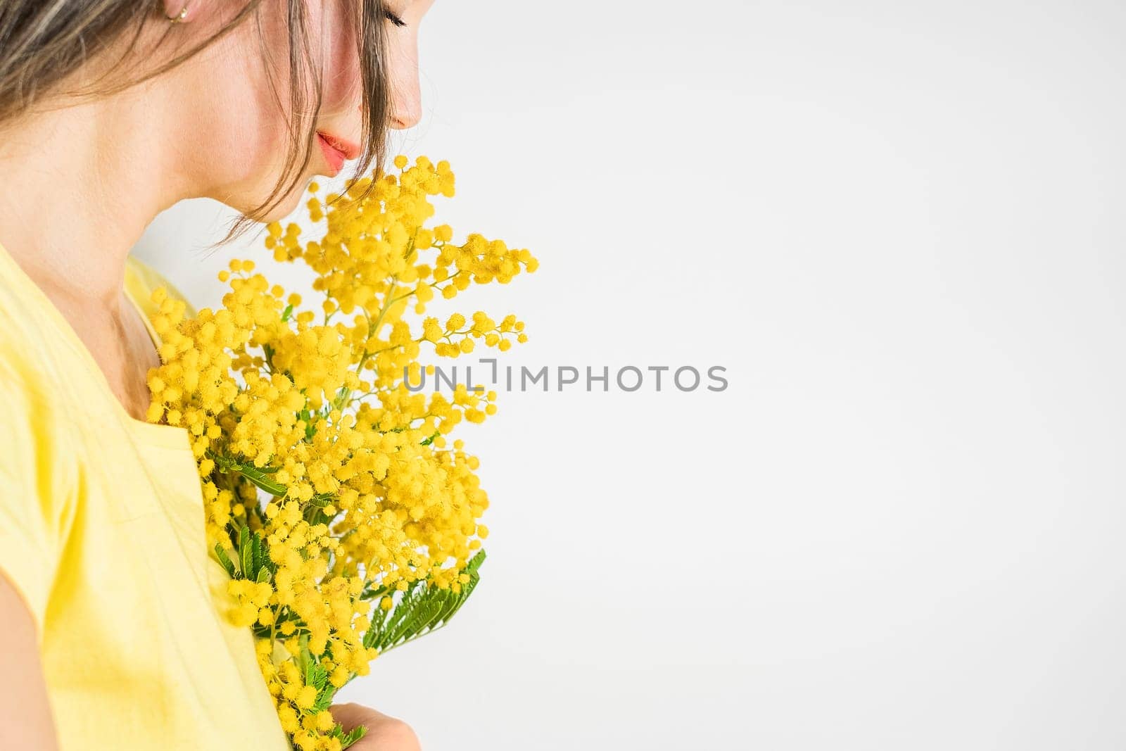 Beautiful young woman with mimosa flowers on white background. Copy space
