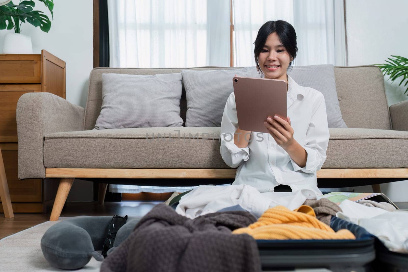 Young woman check baggage lists on tablet to prepare for traveling trip.