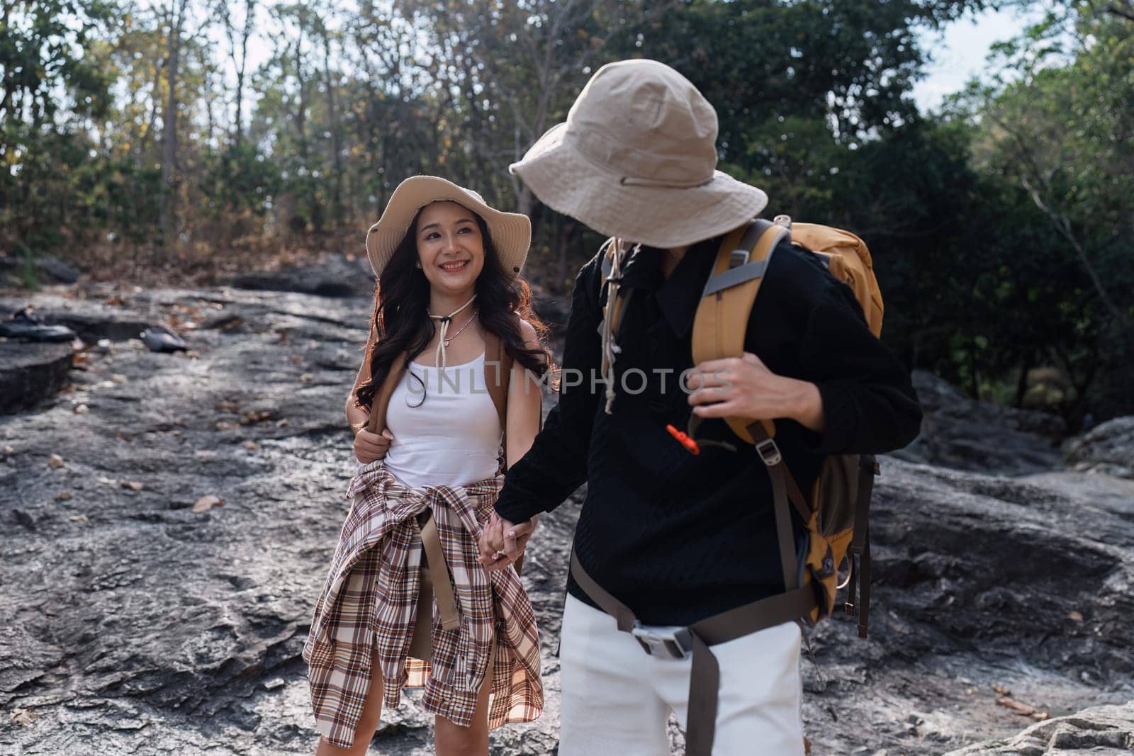 Happy LGBT Lesbian couple Travelers Hiking with Backpacks in waterfall Trail. LGBT Lesbian Couple Hikers with backpacks walks in mountains in vacation.