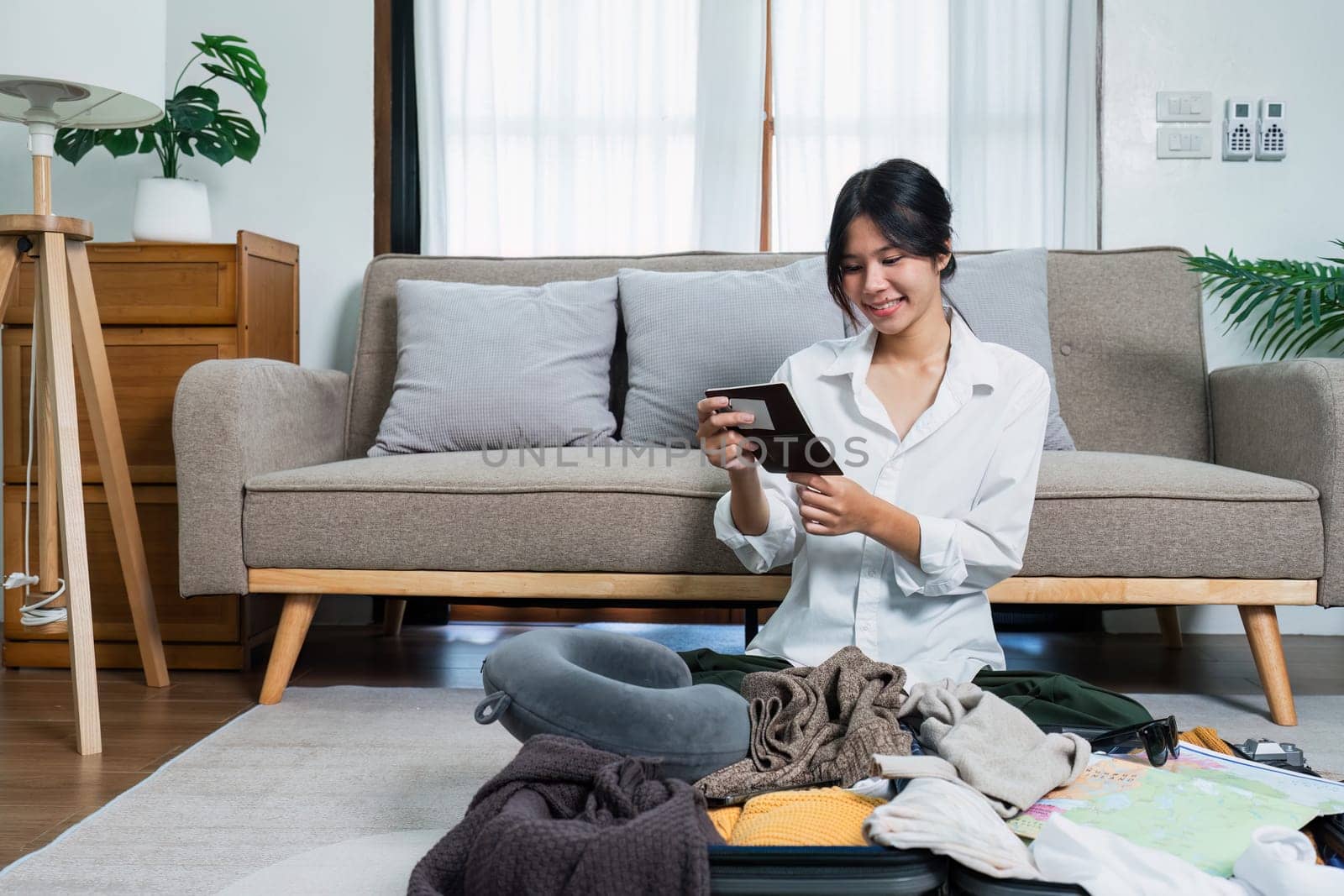 Young woman check baggage lists on notebook to prepare for traveling trip.