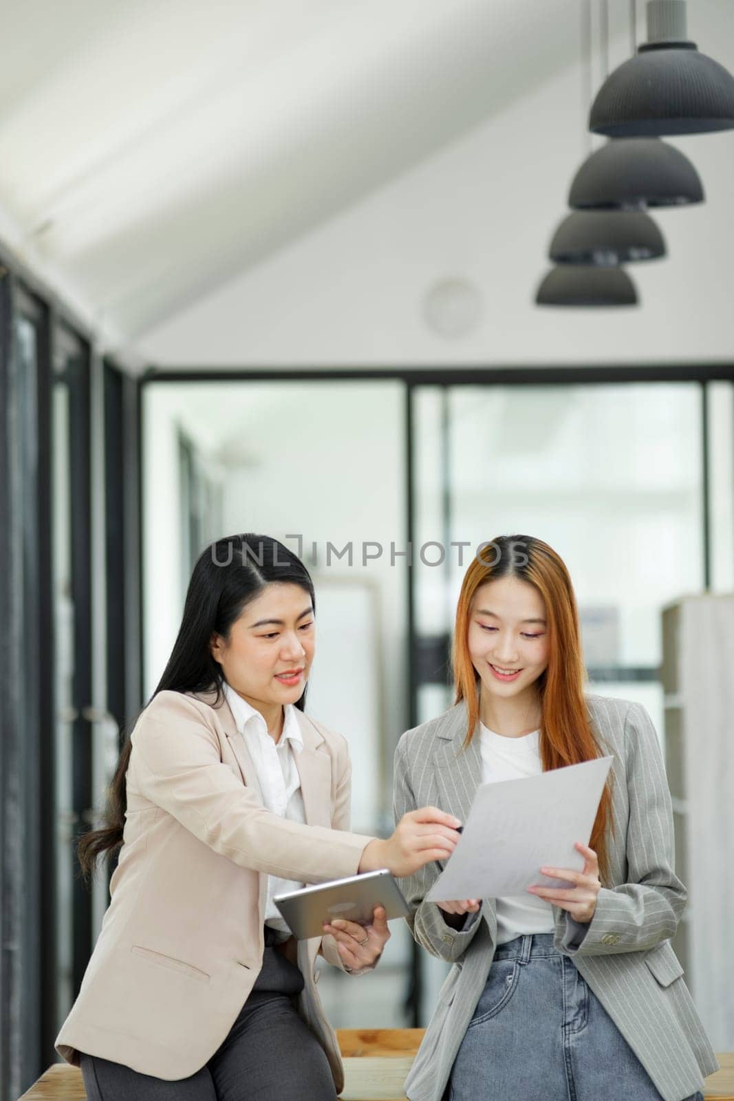 Two engaging businesswomen enjoying a casual conversation while holding coffee, illustrating a relaxed corporate culture.