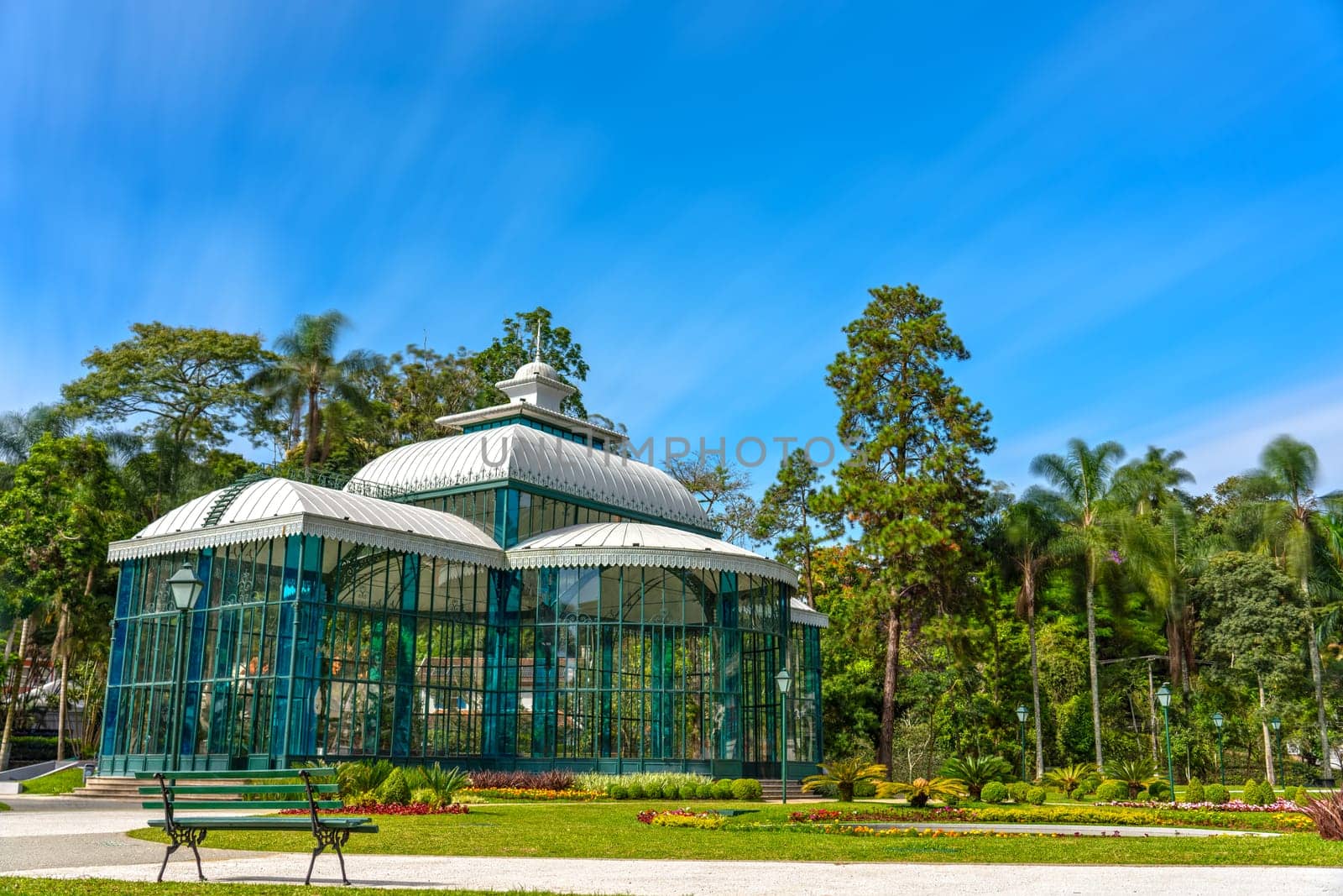An impressive long exposure shot of the Crystal Palace in Petropolis, a beautiful glass palace surrounded by trees and blue skies, perfect for your next nature-themed project.