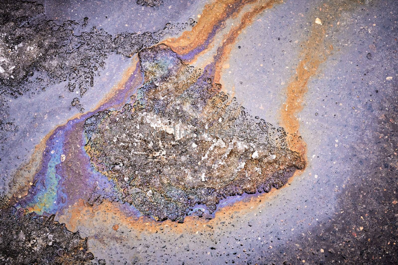 Background of a puddle of gasoline spilled on the road. Gasoline leak. A colorful stain of engine oil on the road